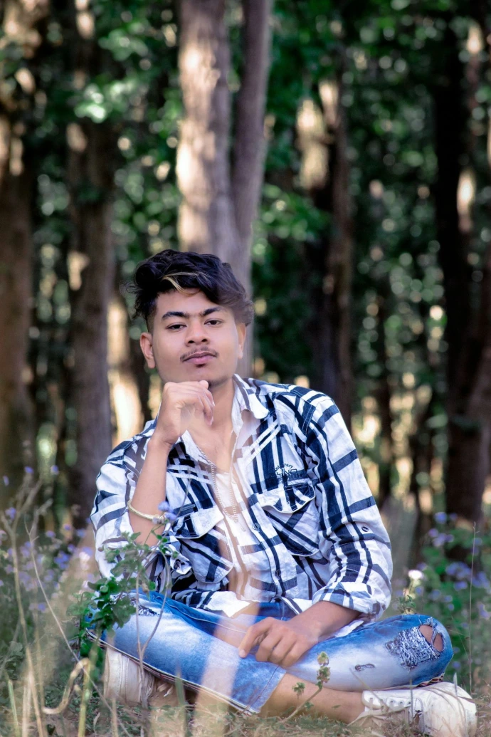 a man sitting on the ground in the woods